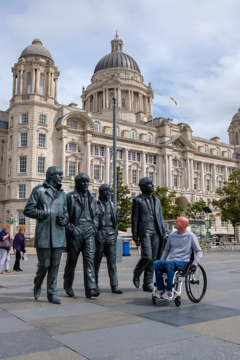 Man in custom wheelchair in Liverpool with beatles statue